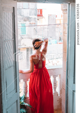 Young attractive woman in red dress on old balcony in apartment in Havana 63684336