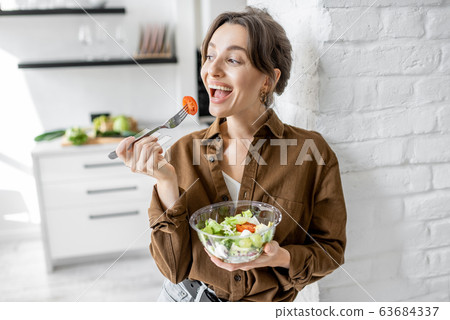 Woman with healthy salad on the kitchen Woman with healthy salad on the kitchen 63684337