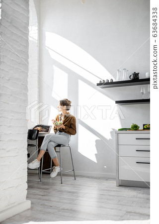 Woman eating salad on the kitchen Woman eating salad on the kitchen 63684338