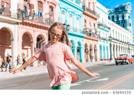 Tourist girl in popular area in Havana, Cuba. Young kid traveler smiling Tourist girl in popular area in Havana, Cuba. Young kid traveler smiling 63684339