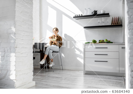 Woman eating salad on the kitchen Woman eating salad on the kitchen 63684340