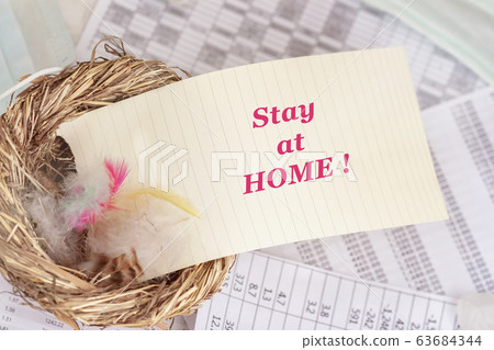 Stay at home, Note of motivational words in nest with feathers, symbol of the house, on background of business tables, self-isolation Stay at home, Note of motivational words in nest with feathers, symbol of the house, on background of business tables, self-isolation 63684344