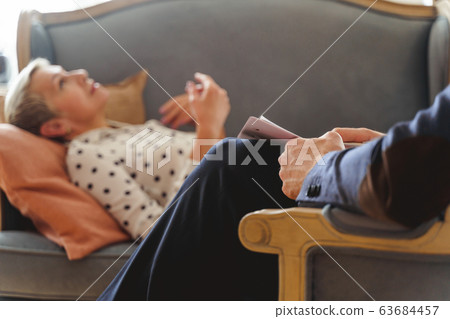 Patient with an absent-minded look lying on the couch 63684457