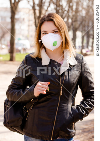 Young beautiful woman in a protective mask walks 63685463