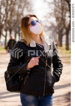 Young woman in a protective mask is walking Young woman in a protective mask is walking 63685475