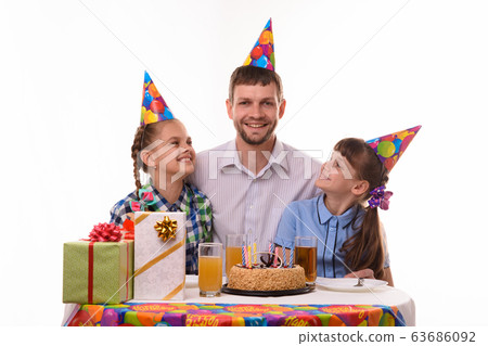 Two girls happily look at dad at the festive table 63686092