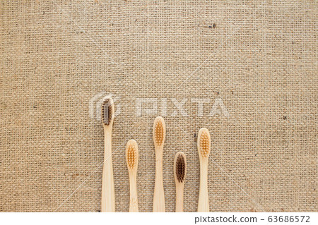 Natural bamboo toothbrushes on rustic burlap background Natural bamboo toothbrushes on rustic burlap background 63686572