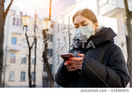 Pportrait of woman in protective medical mask using smart phone on empty european streets. Health and safety, N1H1 coronavirus, covid-19, virus protection care and medical concept. Pan left shot. Pportrait of woman in protective medical mask using smart phone on empty european streets. Health and safety, N1H1 coronavirus, covid-19, virus protection care and medical concept. Pan left shot. 63686805