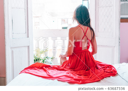 Young attractive woman in red dress on old balcony in apartment in Havana Young attractive woman in red dress on old balcony in apartment in Havana 63687336