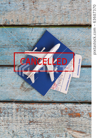 airplane, passport and tickets with a stamp in red text CANCELED on a blue wooden background airplane, passport and tickets with a stamp in red text CANCELED on a blue wooden background 63687370