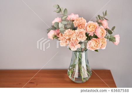 Flowers in glass vase on wooden table. Fresh cut flowers for decoration home. Delivery flower. 63687588