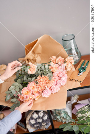 Woman unpack flower set on wooden table. Fresh cut flowers for decoration home. Delivery flower. Woman unpack flower set on wooden table. Fresh cut flowers for decoration home. Delivery flower. 63687604