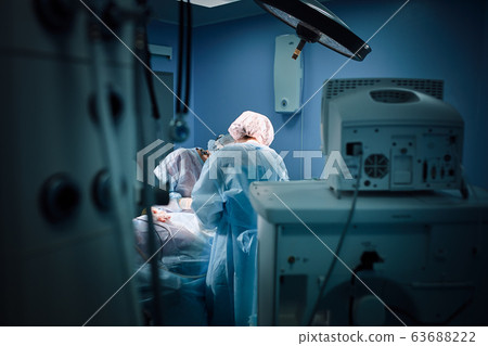 In the hospital operating room. An international team of professional surgeons and assistants works in a modern operating room. Professional doctors celebrate successfully saved lives. In the hospital operating room. An international team of professional surgeons and assistants works in a modern operating room. Professional doctors celebrate successfully saved lives. 63688222