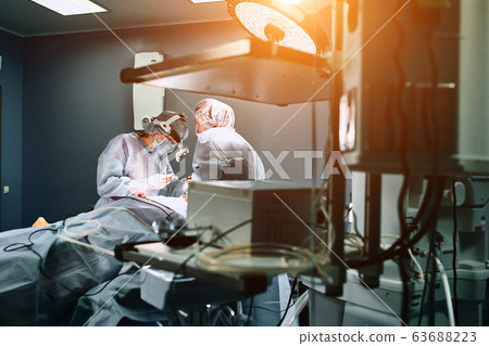 In the hospital operating room. An international team of professional surgeons and assistants works in a modern operating room. Professional doctors celebrate successfully saved lives. In the hospital operating room. An international team of professional surgeons and assistants works in a modern operating room. Professional doctors celebrate successfully saved lives. 63688223