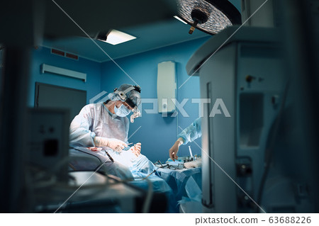 In the hospital operating room. An international team of professional surgeons and assistants works in a modern operating room. Professional doctors celebrate successfully saved lives. In the hospital operating room. An international team of professional surgeons and assistants works in a modern operating room. Professional doctors celebrate successfully saved lives. 63688226