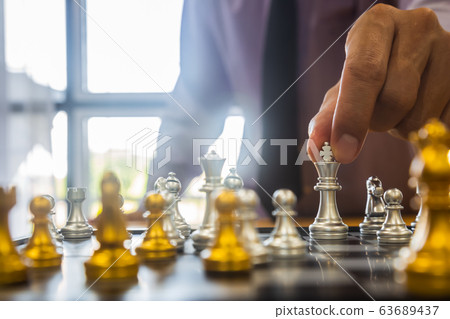 Chess game on chess board behind business man 63689437