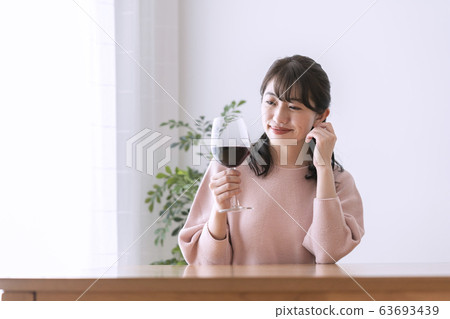 A woman looking at a glass of red wine 63693439