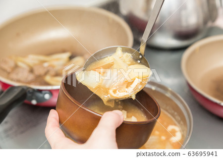 Hand of a woman who puts miso soup with lots of ingredients Hand of a woman who puts miso soup with lots of ingredients 63695941