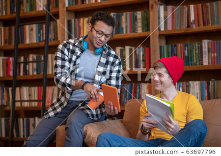 Dark-haired man in eyeglasses showing something on his tablet 63697796