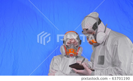 Scientist virologist in respirator makes write in an tablet computer with stylus. Man and woman wearing protective medical mask. Chroma key blue. 63701190