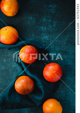 Flat lay food composition with blood oranges on a dark blue background. Flat lay food composition with blood oranges on a dark blue background. 63701443