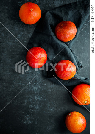 Flat lay food composition with blood oranges on a dark blue background. Flat lay food composition with blood oranges on a dark blue background. 63701444