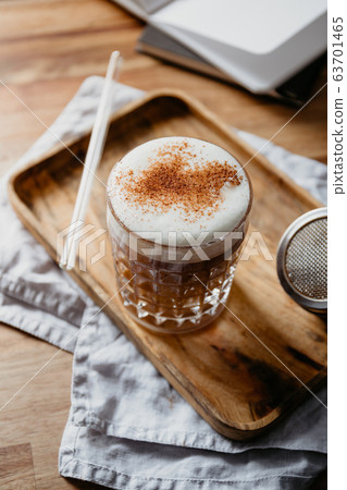 Cup of latte served with glass tube on a wooden  work desk. Coffee break concept. 63701465