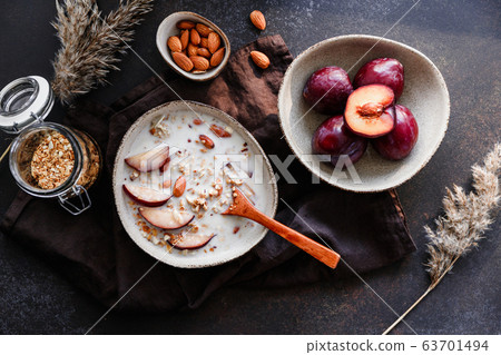 High angle view of morning porridge with almond and sliced plum. Healthy energy breakfast. 63701494