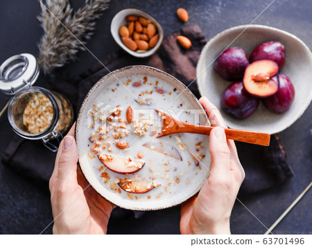 High angle view of morning porridge with almond and sliced plum. Healthy energy breakfast. 63701496
