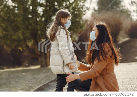 Mother with daughter walks outside in masks 63702178