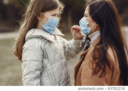 Mother with daughter walks outside in masks 63702216