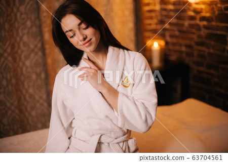 Middle shot portrait of smiling young woman in white bathrobe 63704561
