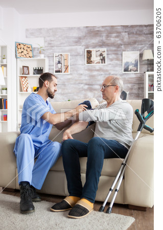 Young assistant in nursing home checking the blood pressure 63706205