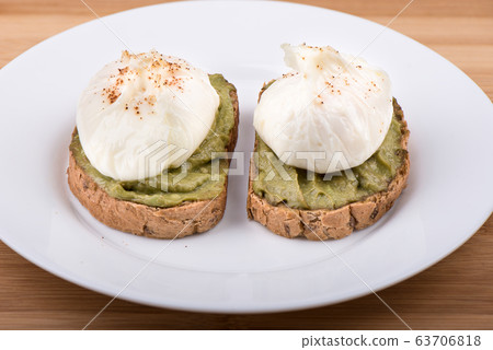 Sandwiches with poached eggs and avocado paste on cereal bread 63706818