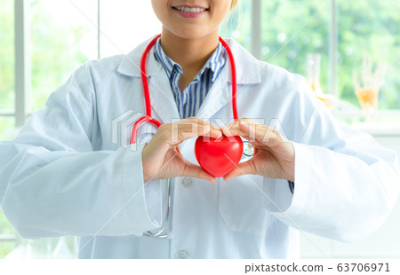 Woman doctor holding a red heart, health medical Woman doctor holding a red heart, health medical 63706971
