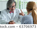 Serious doctor holding and talking with a female 63706973