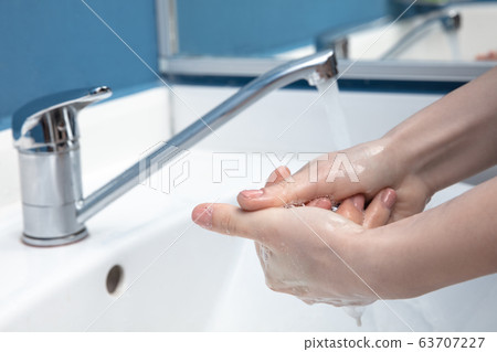 Woman washing hands carefully in bathroom close up. Prevention of infection and pneumonia virus spreading 63707227