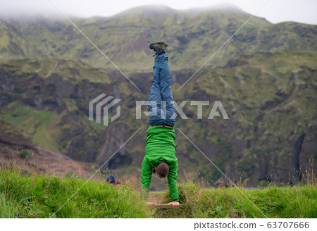 young guy standing on his hands with fogy mountain background on the way of Laugavegur trail Iceland young guy standing on his hands with fogy mountain background on the way of Laugavegur trail Iceland 63707666