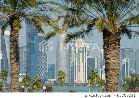 Panoramic view of modern skyline of Doha through blurred palm trees. Qatar on sunny day Panoramic view of modern skyline of Doha through blurred palm trees. Qatar on sunny day 63709281