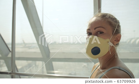 Woman caucasian at airport with wearing protective medical mask on head against the background of the plane. Coronavirus sars-cov-2 covid-19. Woman caucasian at airport with wearing protective medical mask on head against the background of the plane. Coronavirus sars-cov-2 covid-19. 63709926
