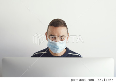 man using a computer wearing a surgical mask man using a computer wearing a surgical mask 63714767