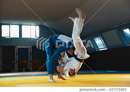 Two young judo fighters in kimono training martial arts in the gym with expression, in action and motion 63715065