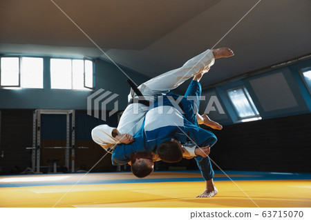 Two young judo fighters in kimono training martial arts in the gym with expression, in action and motion Two young judo fighters in kimono training martial arts in the gym with expression, in action and motion 63715070