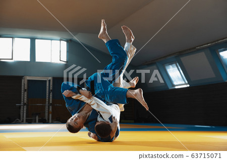 Two young judo fighters in kimono training martial arts in the gym with expression, in action and motion 63715071
