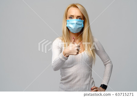 Studio portrait of young woman wearing a face protective mask isolated on gray background - flu virus epidemic protection, dust or pollen allergy, air pollution Studio portrait of young woman wearing a face protective mask isolated on gray background - flu virus epidemic protection, dust or pollen allergy, air pollution 63715271