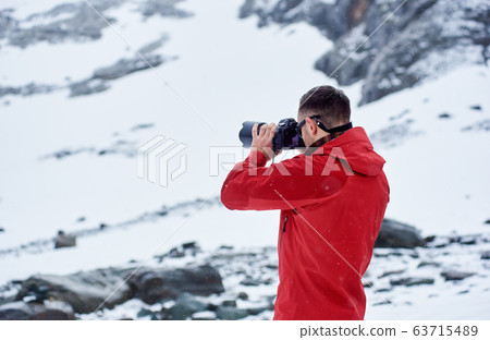 Young man taking picture in winter mountains. Young man taking picture in winter mountains. 63715489