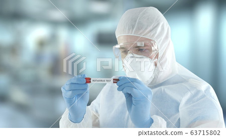 Unknown laboratory assistant wearing protection gear examines vial with rotavirus blood test 63715802