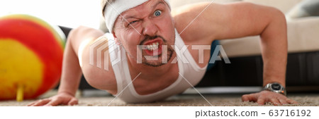 Funny grimacing man making push-ups home 63716192