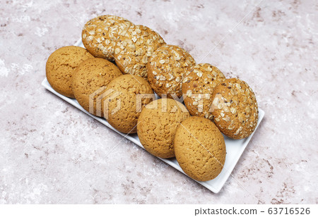 Set of various american style cookies on a light concrete background. Shortbread with confetti, sesame seed, peanut butter, oatmeal and chocolate chip cookies. 63716526