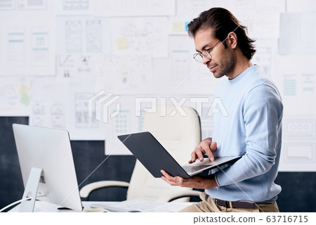Modern man using laptop in office Modern man using laptop in office 63716715